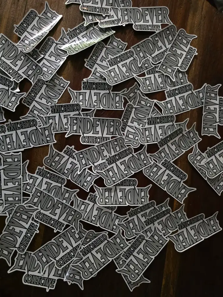 Endever Collective die-cut sticker, silver on faded black.
